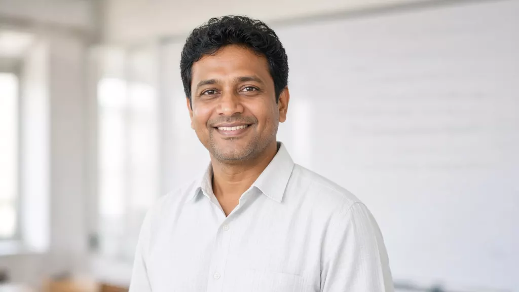 Portrait of a smiling physics teacher in a white shirt in a bright classroom